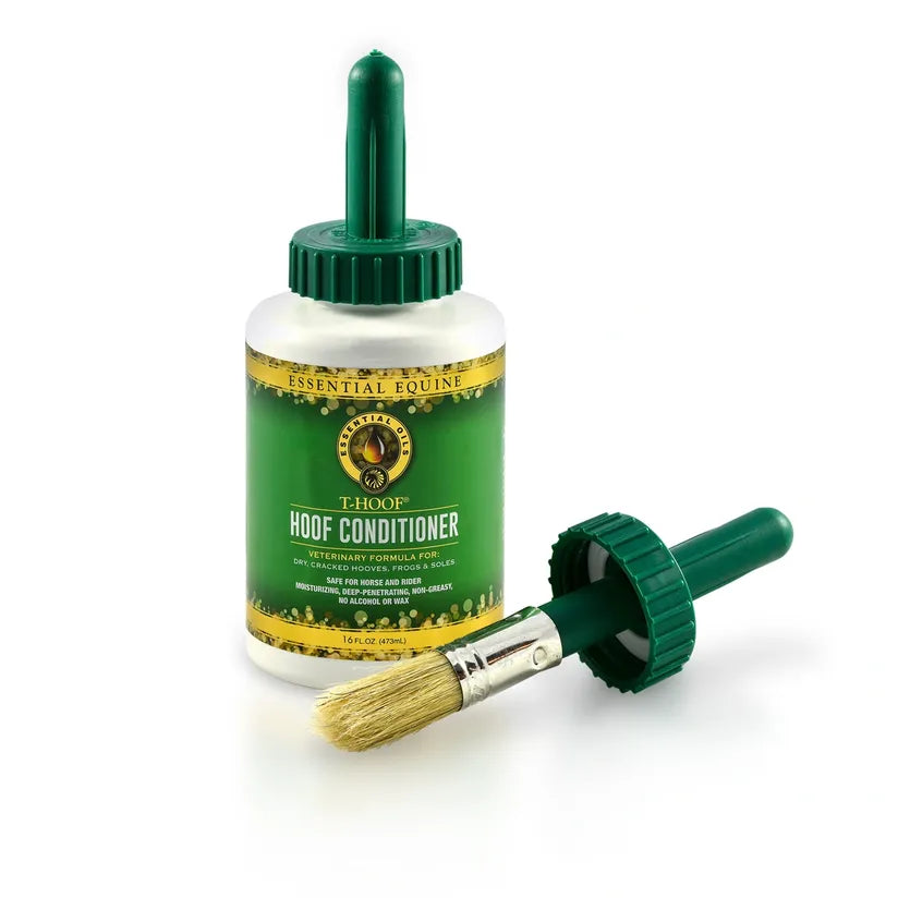 A bottle of Essential Equine T-HOOF Hoof Conditioner with a green cap and a brush with a wooden handle lying in front of it.