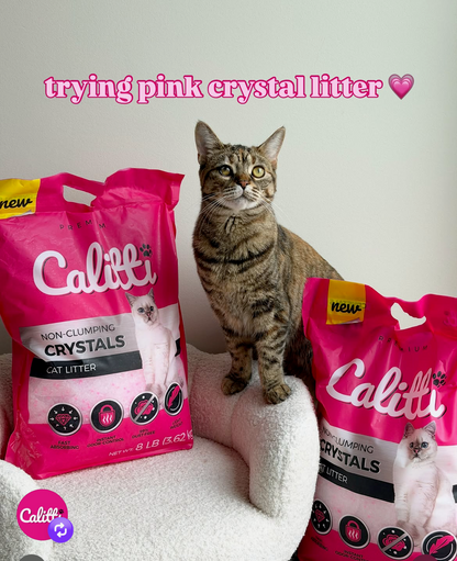 Cat sitting next to Caletti pink crystal litter bags with text 'trying pink crystal litter' on a light background.